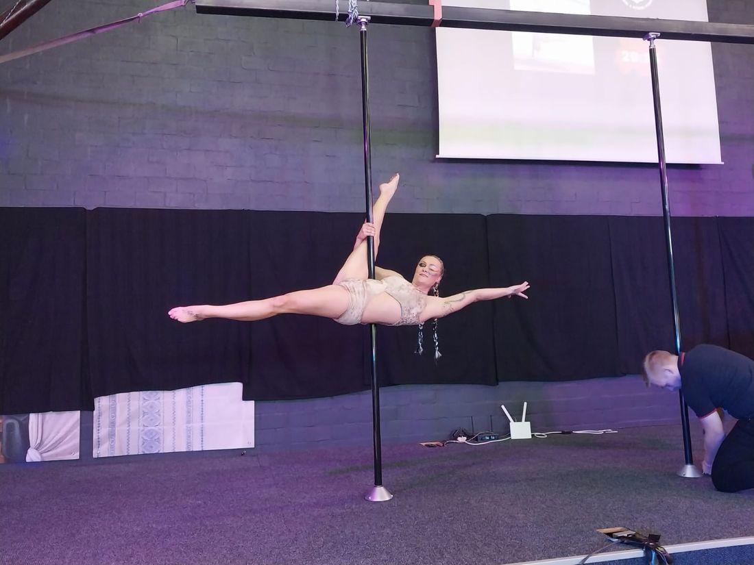 Pole artist performing a split hold on stage during the showcase